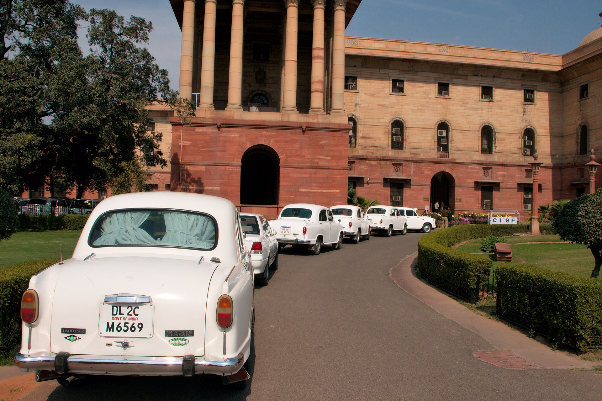 Row of Ambassador official cars parked outside a government building