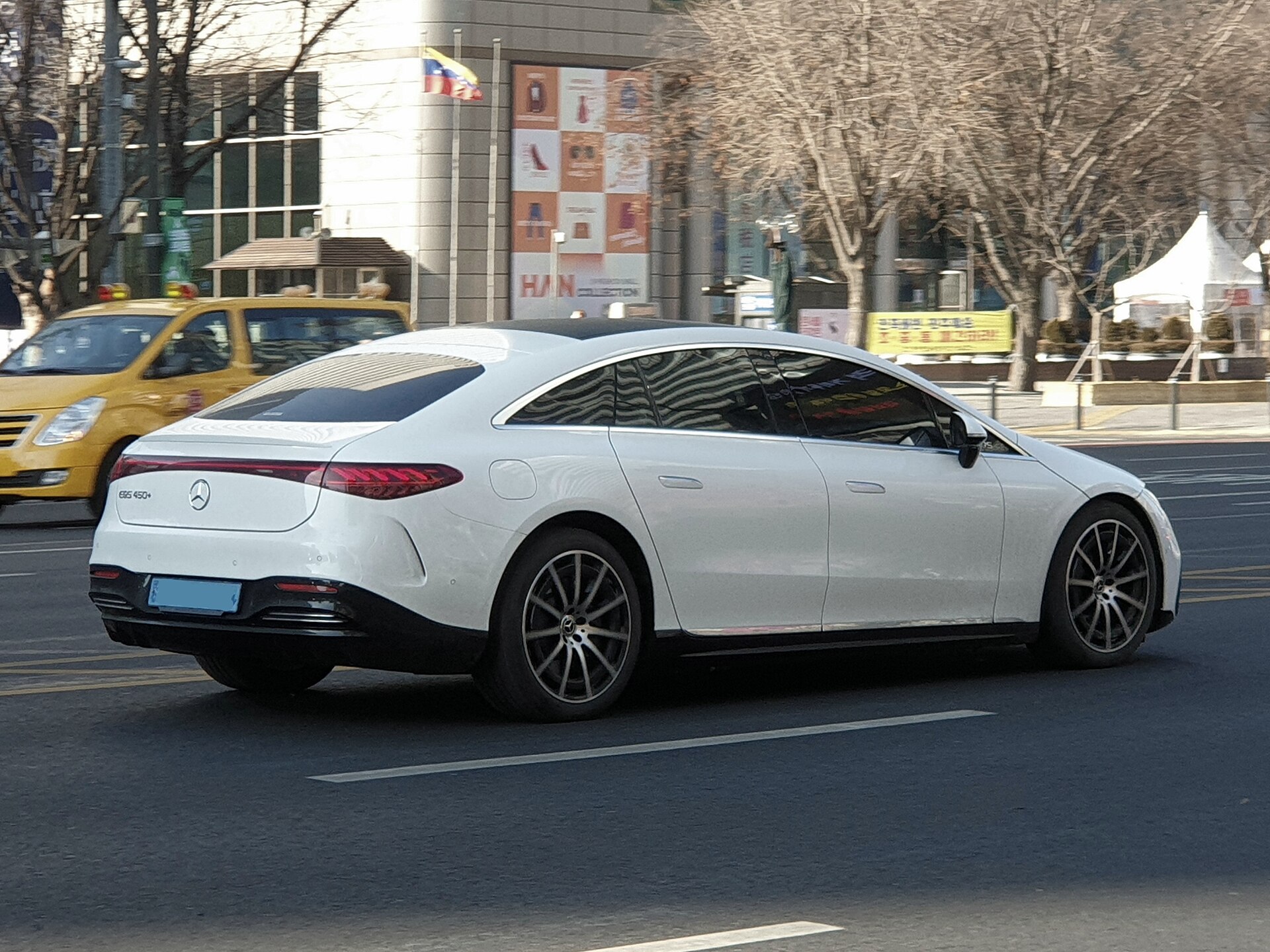 White Mercedes-Benz EQS 450+, side and rear view of the arched roof